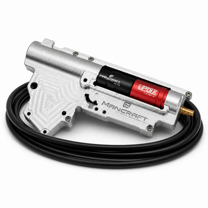 Mancraft PDiK V2 Gen.3 avec gearbox V2 CNC argentée posée sur flexible pneumatique noir enroulé, vue diagonale